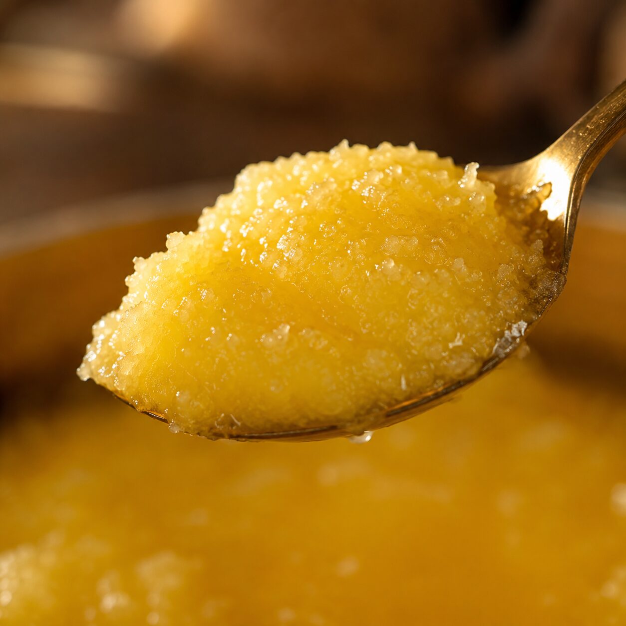 Close-up of grainy golden bilona ghee on a spoon